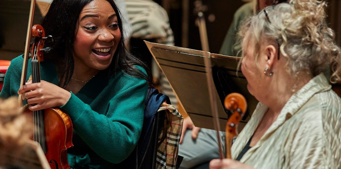 An LSO violinist laughing with an LSO Pathways violinist